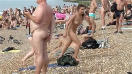 Вуайерист посреди большого количества голых нудистов на пляже